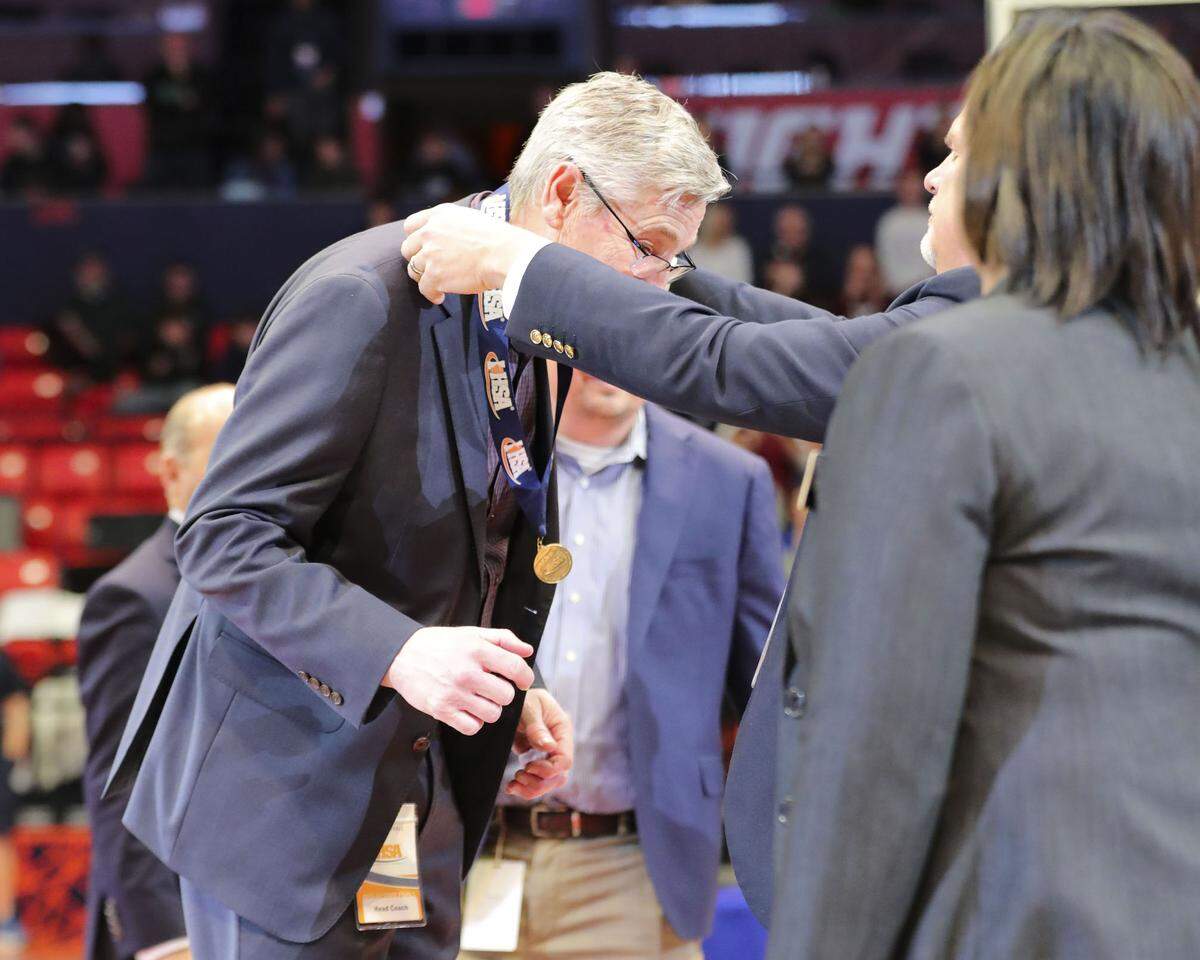 Gibault boys basketball head coach Dennis Rueter has the championship medal placed around his neck after Saturday’s IHSA Class 1A state title game against Scales Mounds at the State Farm Center on the campus of the University of Illinois. Gibault ultimately prevailed 65-45 to claim the state title in Rueter’s 43rd season as the program’s coach.