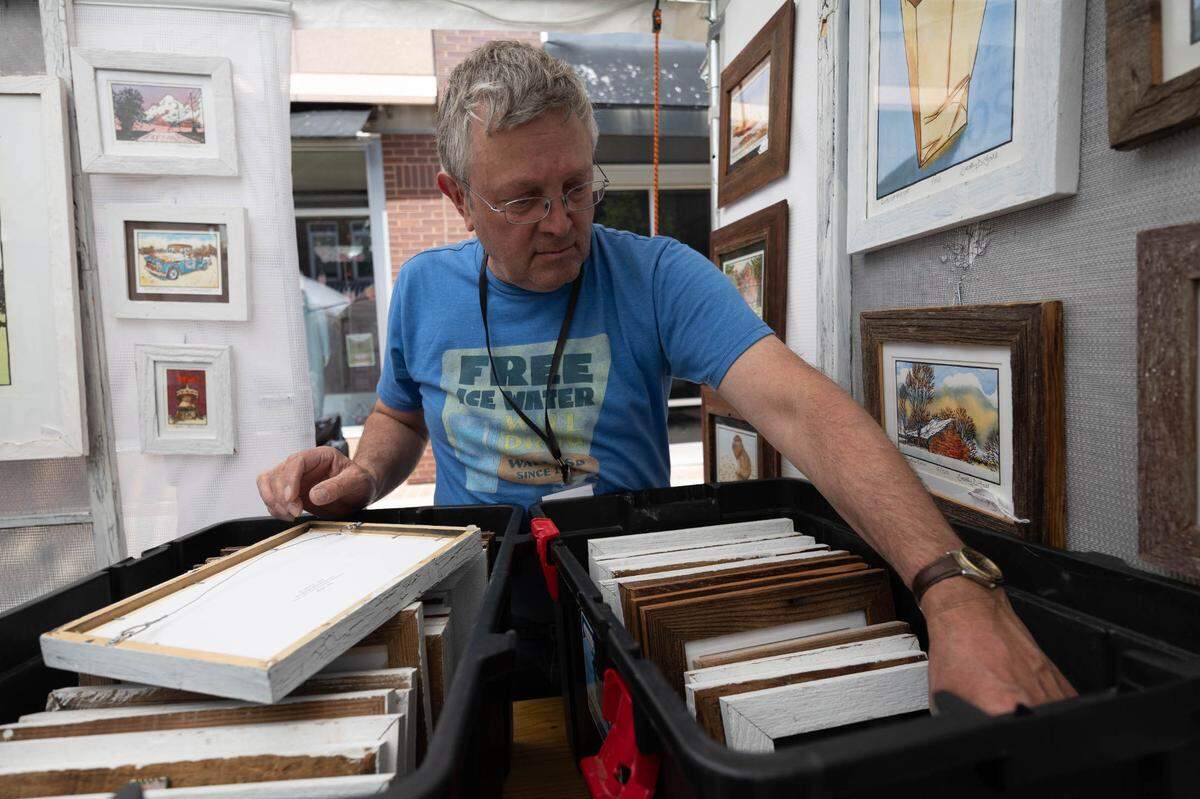 Minnesota artist Brad Hall sets out his paintings in preparation of last year’s Art on the Square event.