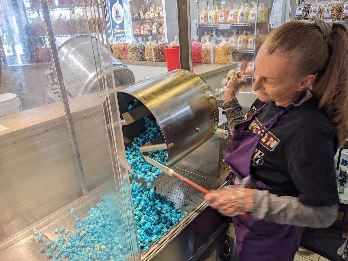 After combining the popcorn with the blue raspberry candy, Cindy Erwin pours out the mixture that will be used to make the new Eclipse flavor at Abe’s Gourmet Popcorn.