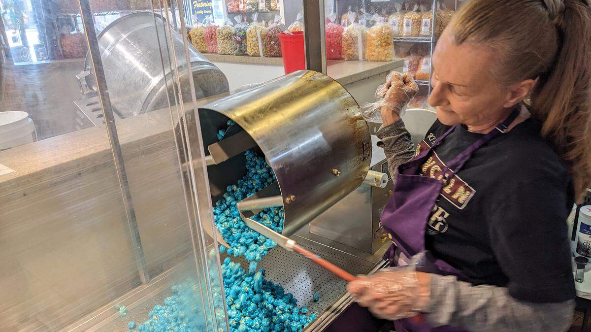After combining the popcorn with the blue raspberry candy, Cindy Erwin pours out the mixture that will be used to make the Eclipse flavor at Abe’s Gourmet Popcorn.