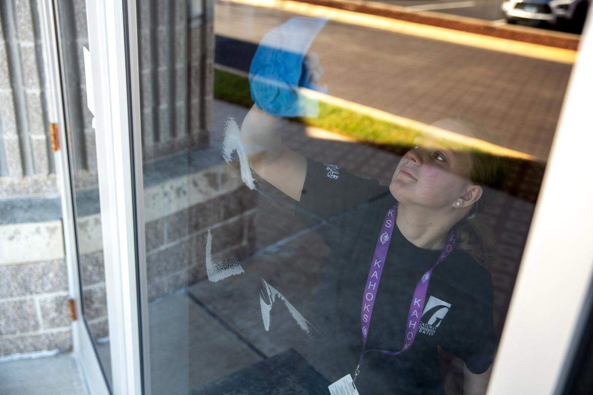 Mackensie Walker, 17, cleans windows in preparation for an upcoming event on Tuesday, Nov. 14, 2023, at the Gateway Convention Center in Collinsville, Ill. Walker is a senior at Collinsville High School and a part of an apprenticeship program for students with disabilities.