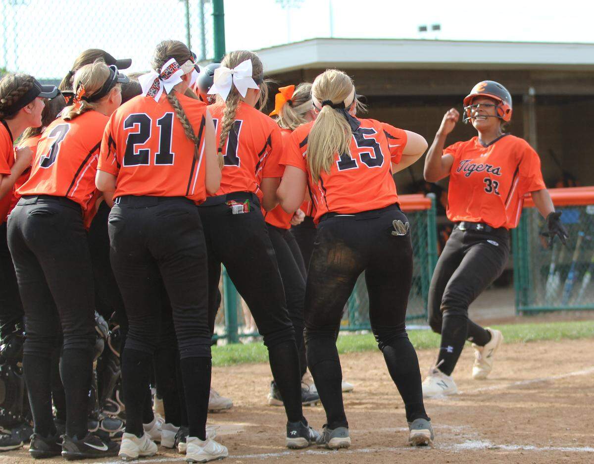 Edwardsville sophomore Maria Smith is greeted at home plate by teammates after hitting a fourth-inning home run over the scoreboard. The Tigers defeated Belleville East, 3-0, in the class 4A sectional semifinals.