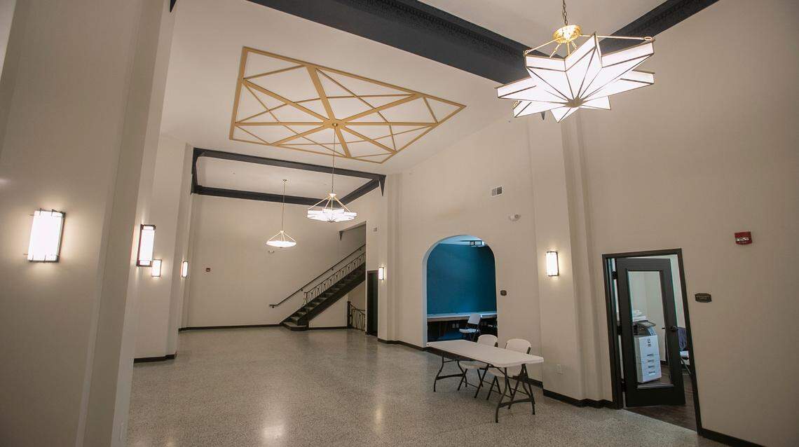 The Lofts on the Square lobby has white walls, ornate navy trim, the original terrazzo floor and art-deco-style chandeliers. An arched doorway leads to what will become a computer lab.