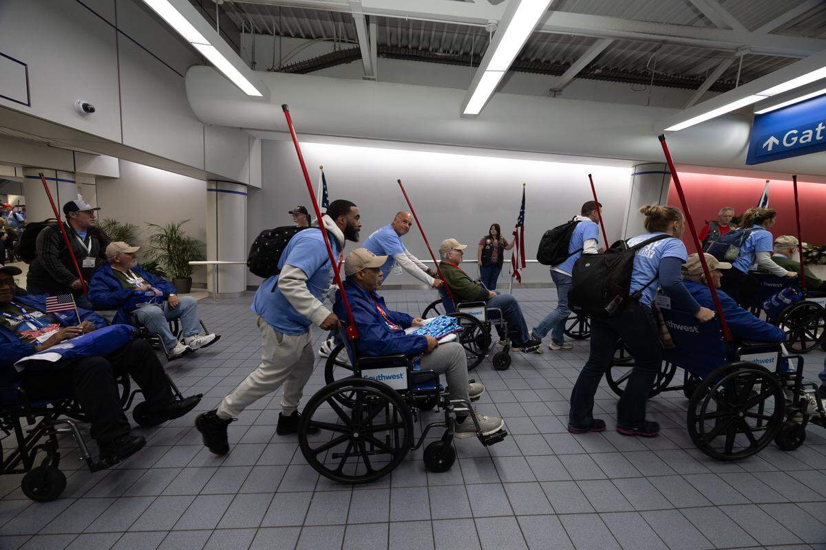 Teams of volunteers push wheelchair-bound veterans as they arrive from the Greater St. Louis Honor Flight.