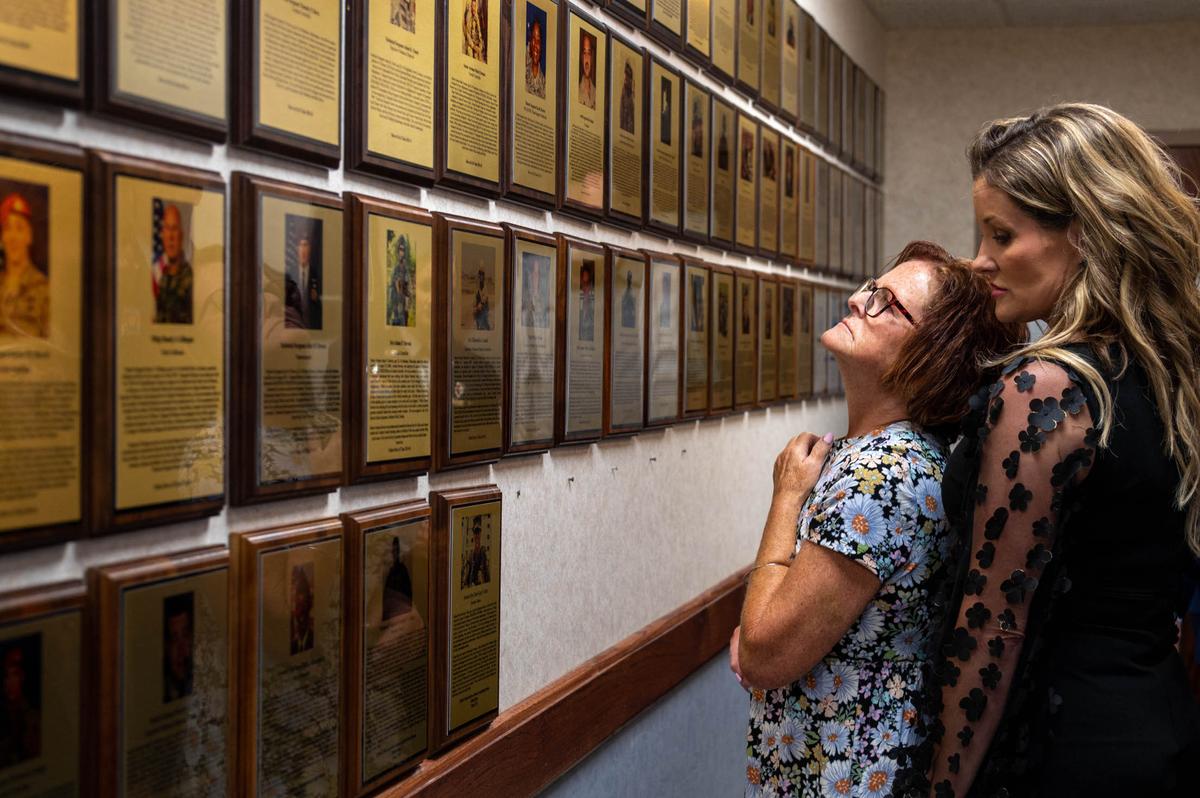 Paula Smith, mother of the late Senior Airman Bradley Smith, observes plaques with Kimberly Hearth, St. Clair County executive director of military affairs, June 17 in the Scott Air Force Base Airman Leadership School building on Scott Air Force Base. Smith came to the ALS building with Scott leadership to see the dedications given to her son.