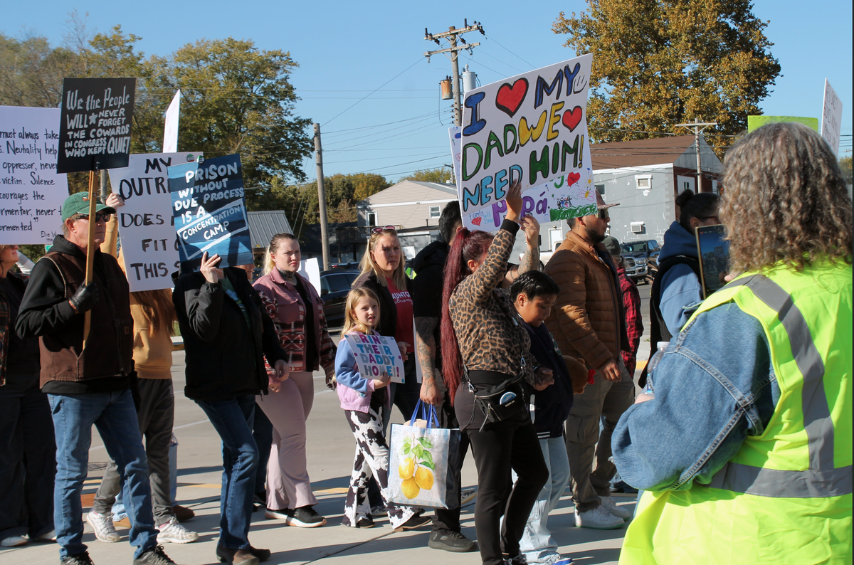 Chelsa Pruden, at right, captures marchers with her phone Sunday during a rally for Ismael Ayuzo Sandoval, who was taken into custody by U.S. Immigration and Customs Enforcement. Among their signs were “Bring their daddy home.”