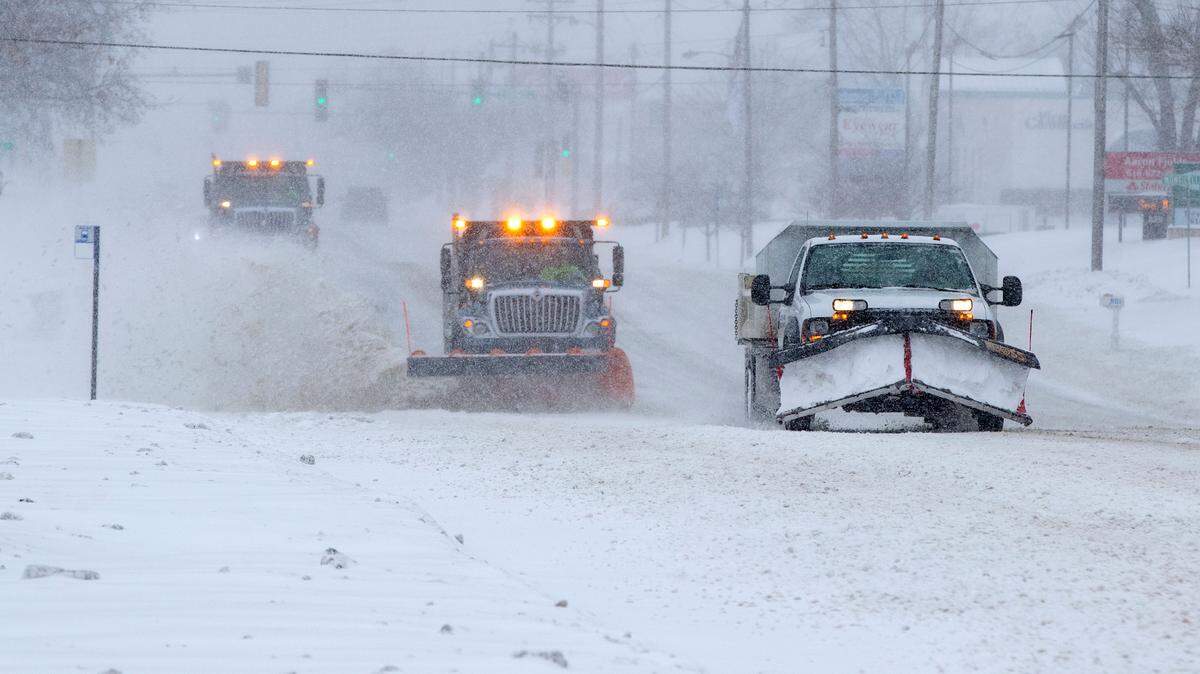 A commercial snow plow operator is followed by two Fairview Heights, Illinois snow plows as they clear the snow on Lincoln Highway in Fairview Heights.