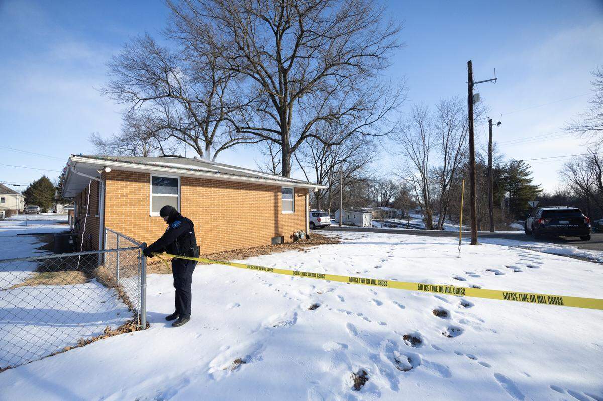 A police officer secures yellow tape around a home on Olive Street in Collinsville on Tuesday morning, hours after a fatal shooting occurred near the garage.