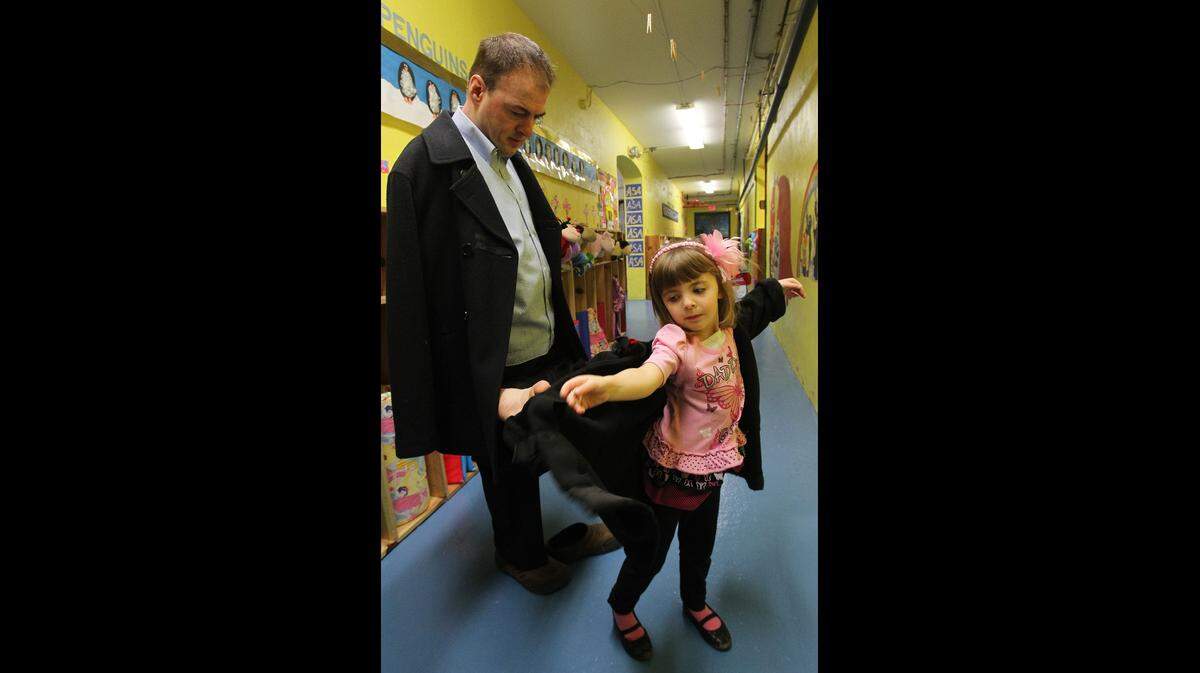 John Foppe helps his 4-year-old daughter, Faith, put on her coat at All Saints Academy in Breese.