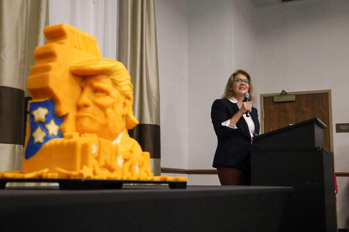 Illinois GOP Chair Kathy Salvi speaks to the Illinois delegation to the 2024 Republican National Convention at a breakfast meeting at a suburban Milwaukee hotel alongside a cheese carving of President Donald Trump and the state of Illinois.
