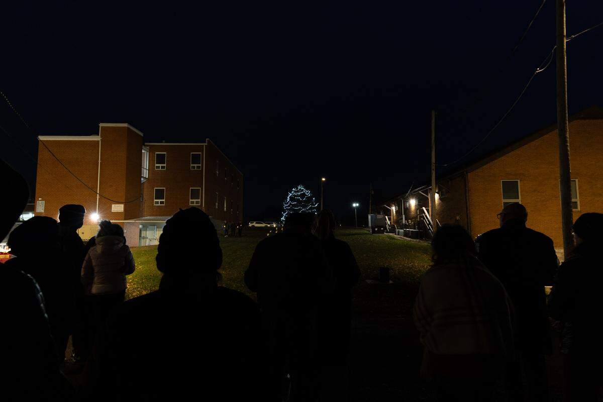 A crowd stares on as a tree (center) is lit in part of a memorial service to loved ones along Belleville’s Illinois Street.