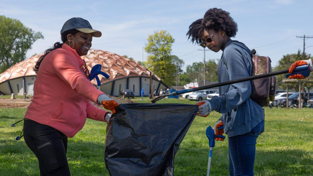 Peyton Kelly (r) and Destiny McCain hold up a trash bag during an Earth Day cleanup in East St. Louis, Ill. on April 20, 2024.