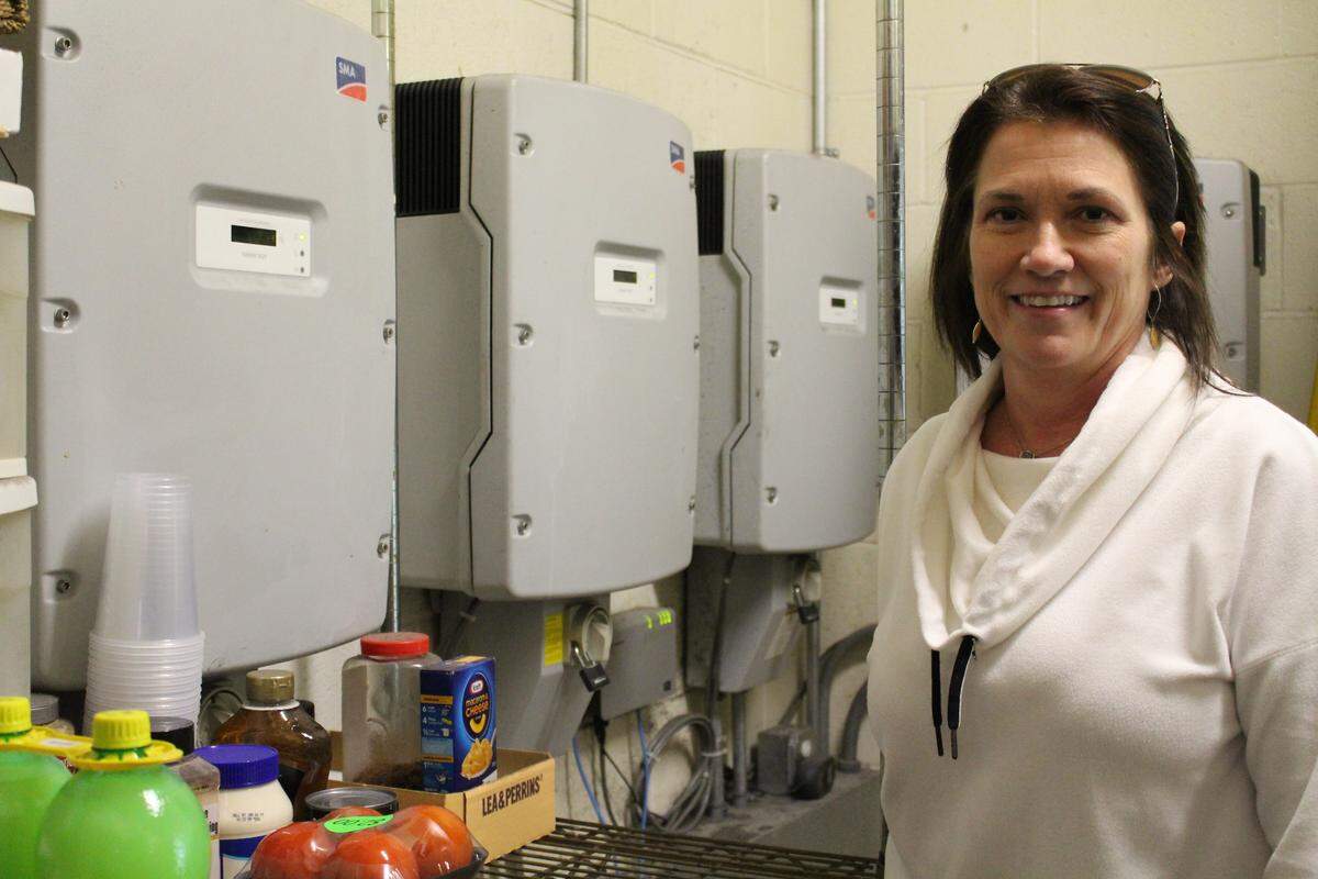 Melinda Kershaw, marketing director for Day & Night Solar in Collinsville, stands next to solar inverters in the Eddie’s Lounge kitchen that turn DC into AC power.