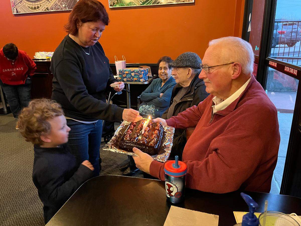 Belleville City Clerk Jenny Meyer, center, lights candles on a 67th birthday cake for former Mayor Mark Eckert on Sunday at Cutter’s Bar & Grill as grandson Noah Eckert, 3, looks on.