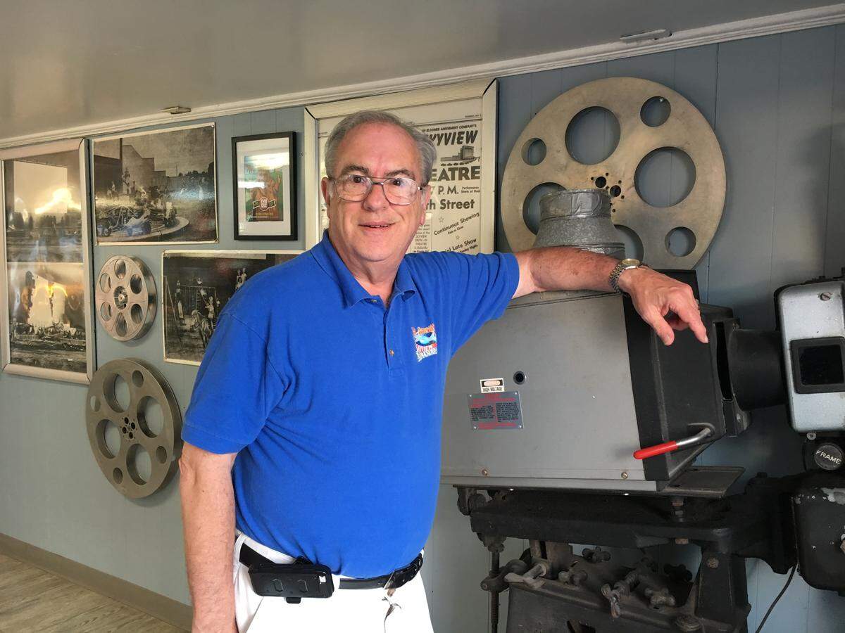 Steve Bloomer stands near the old projector that’s now in the concession stand, along with a wall of memorabilia.