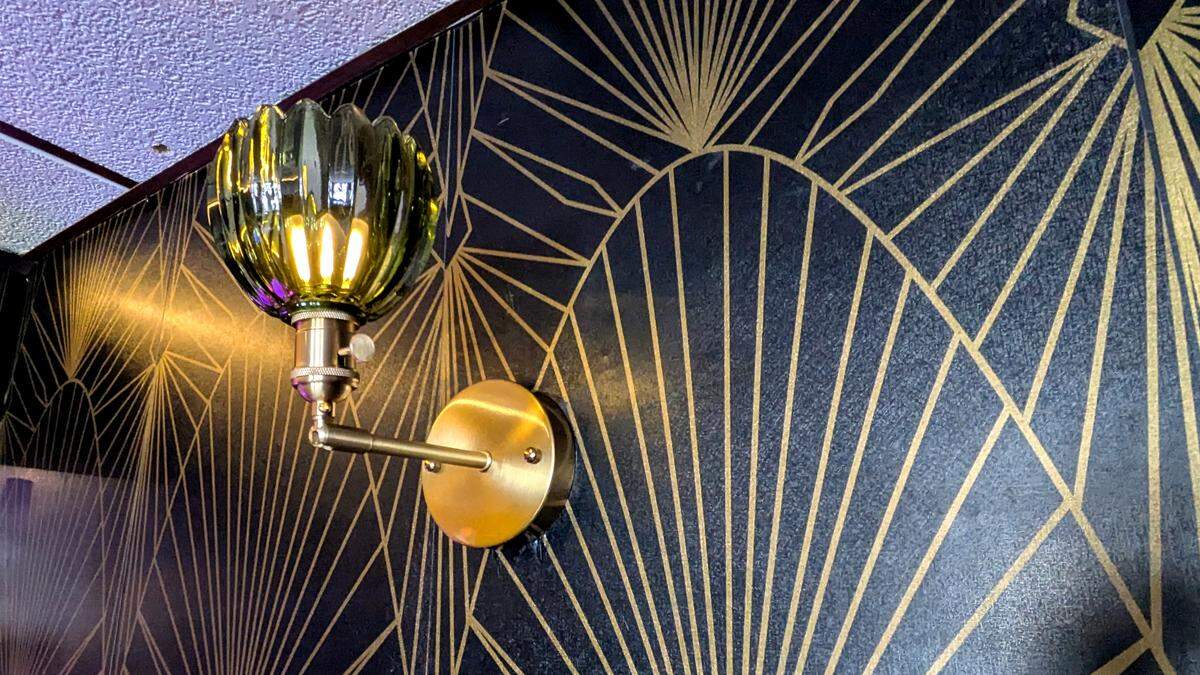 A closer look at the decorative wallpaper and a wall sconce at Rachel’s Sidebar