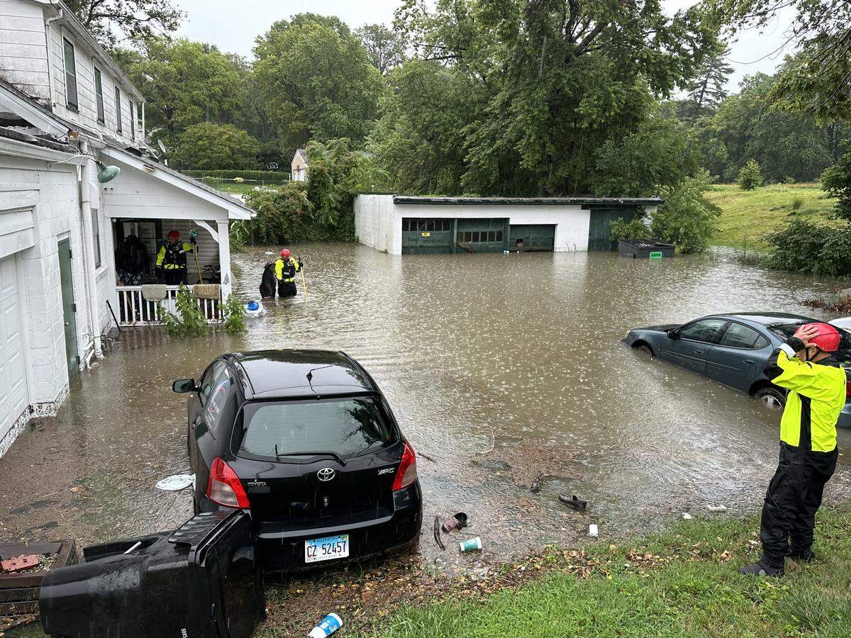 A trio of firefighters guide two residents of an E. Main Street home to safety in Belleville, Ill., on July 16, 2024. The home flooded in about 30 minutes and was caused by a blockage in sewer drains.