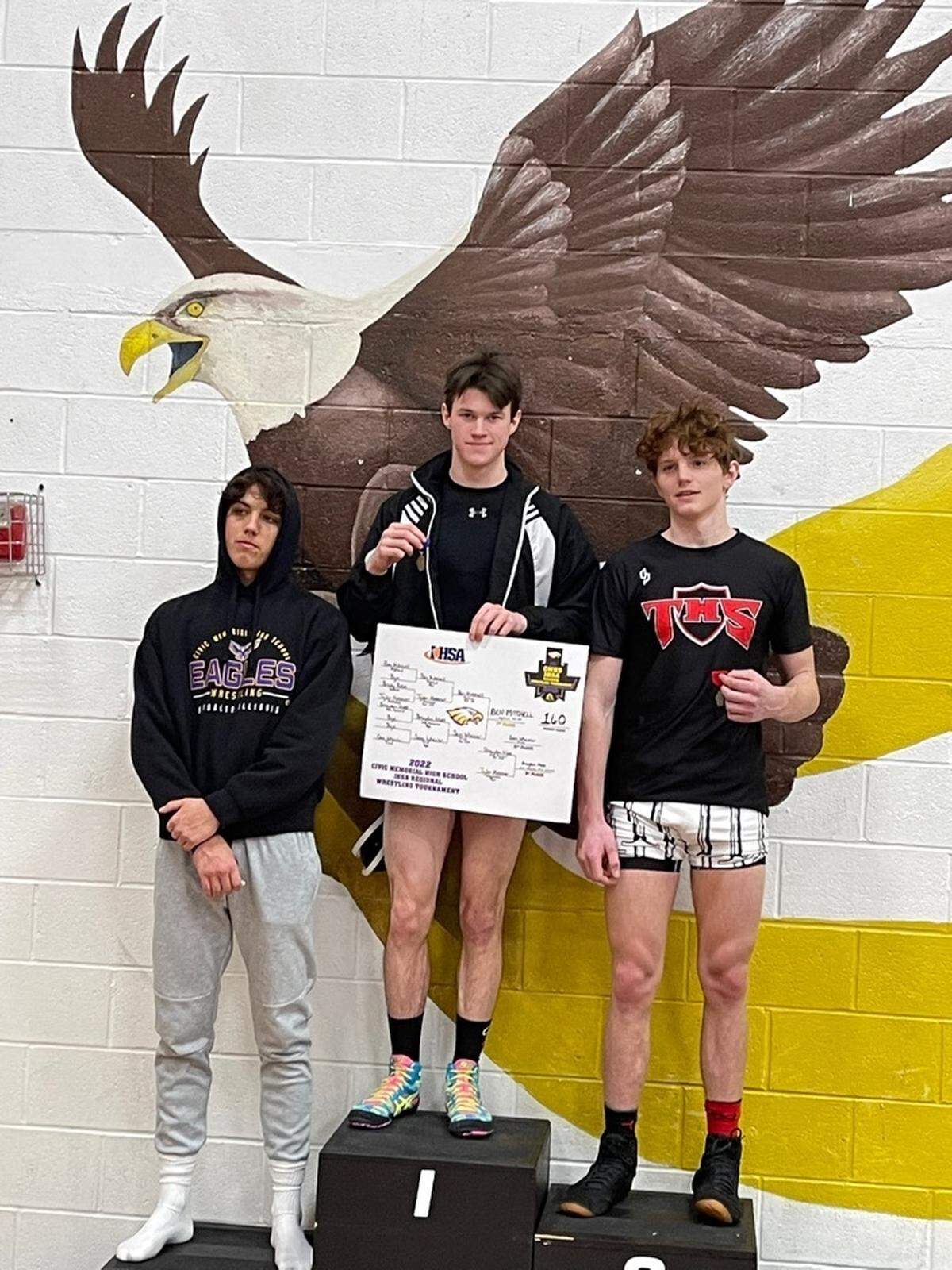 Highland’s Benny Mitchell, top center, is on the podium after winning the 160-pound championship at the IHSA Class 2A regional at Civic Memorial High School on Saturday, Feb. 5. Pictured with Mitchell are Triad’s Sam Wheeler, left, and Civic Memorial’s Brayden Moss, the second and third-place finishers at 160, respectively. Mitchell’s showing helped him advance to sectional competition.