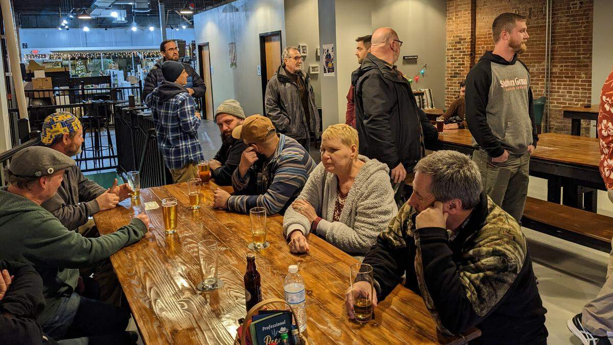 Seated guests enjoy their drinks over conversations at the soft opening of Shoehorn Brewing in Belleville as others wait in line to place orders