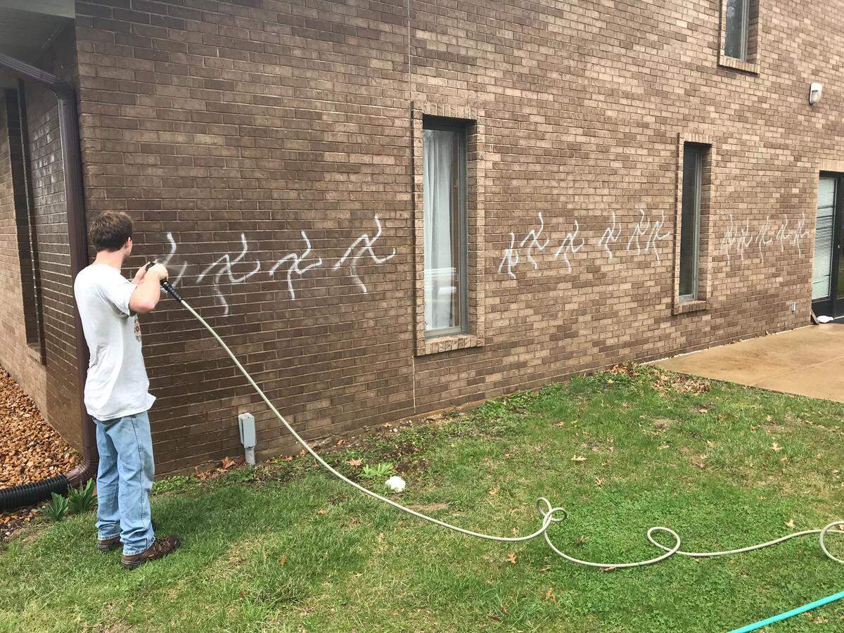 A worker cleans swastikas off the walls of St. Cecilia Catholic Church in Glen Carbon, Ill., after the church was vandalized on Easter night. The man accused of painting swastikas on more than 200 graves and homes in Glen Carbon on Memorial Day weekend has also been charged with vandalizing three churches in the last two months.