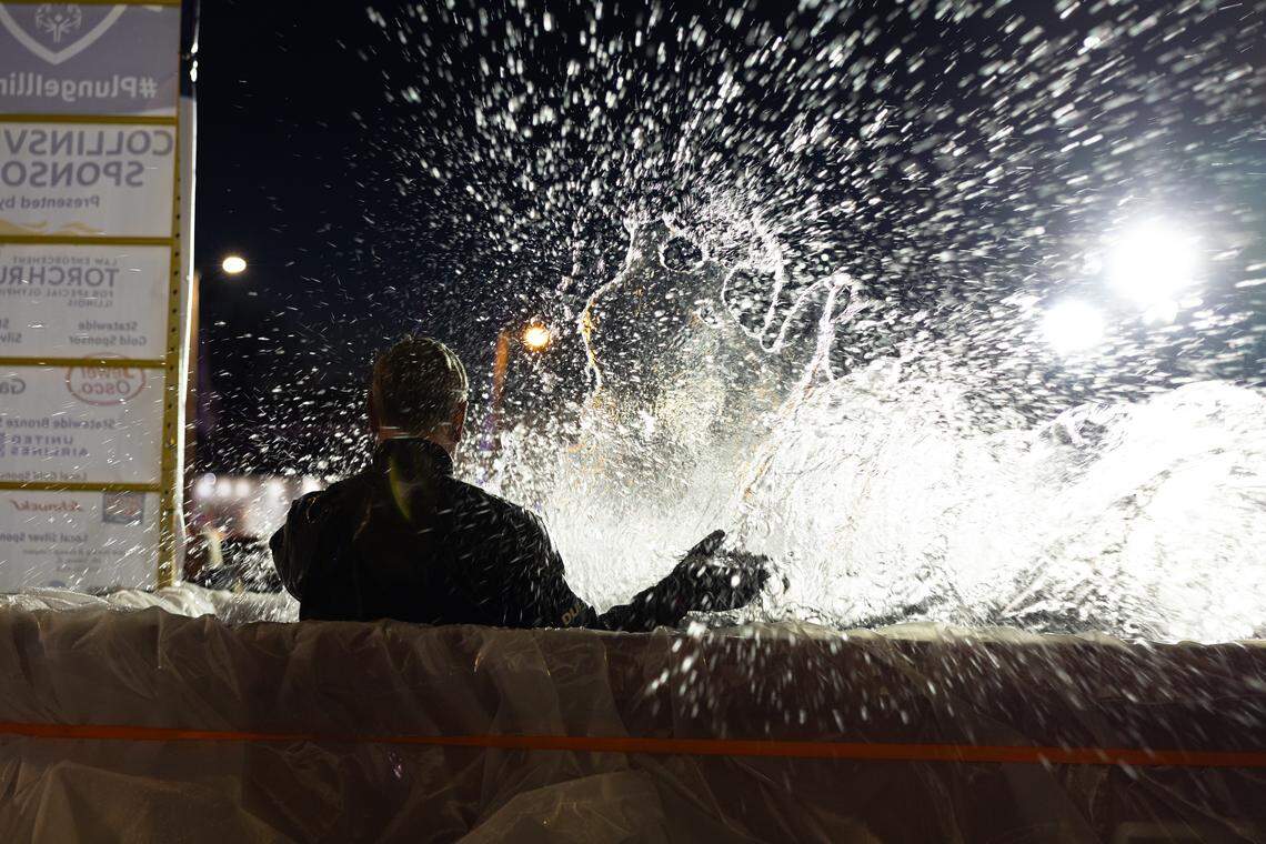 A diver for the O’Fallon Underwater Search and Rescue team stands by as a plunger takes a dive into a dumpster for the Polar Plunge in Collinsville Friday. All around the dumpster was a splash zone, and anyone nearby was in imminent danger of getting soaked.