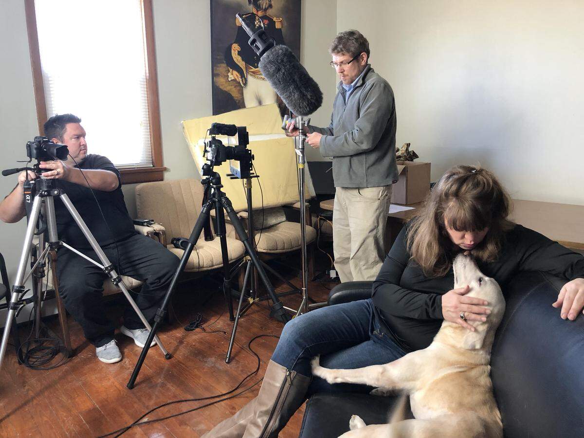 Loretta, a yellow Labrador retriever, and her foster mother, Patty Barney, take a break from filming a Partners for Pets promotional video with Barlow Productions owner Patrick Barlow, center, and videographer Bill Sawalich.