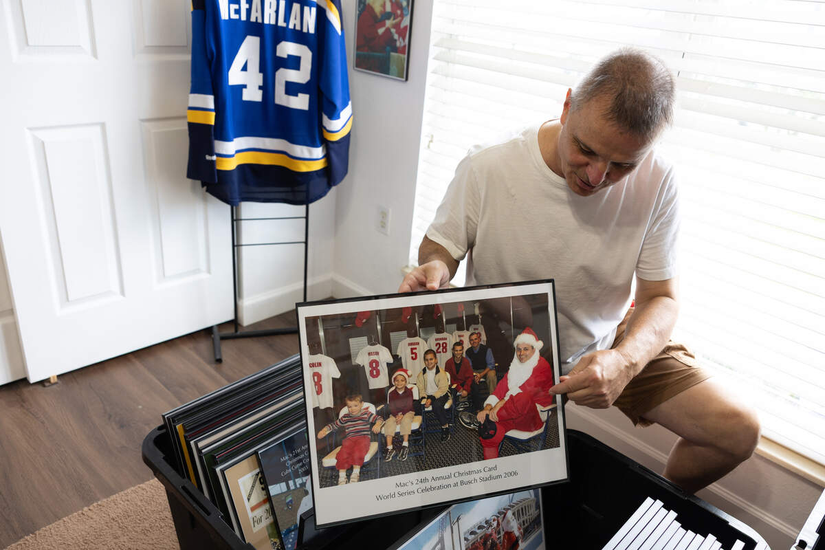 Dave McFarlan holds an old photo of the brothers and their children, staged to look like the famous cover of a 1968 edition of Sports Illustrated that celebrated the Cardinals’ World Series title. “I could tell stories all day about these if you let me,” McFarlan said.