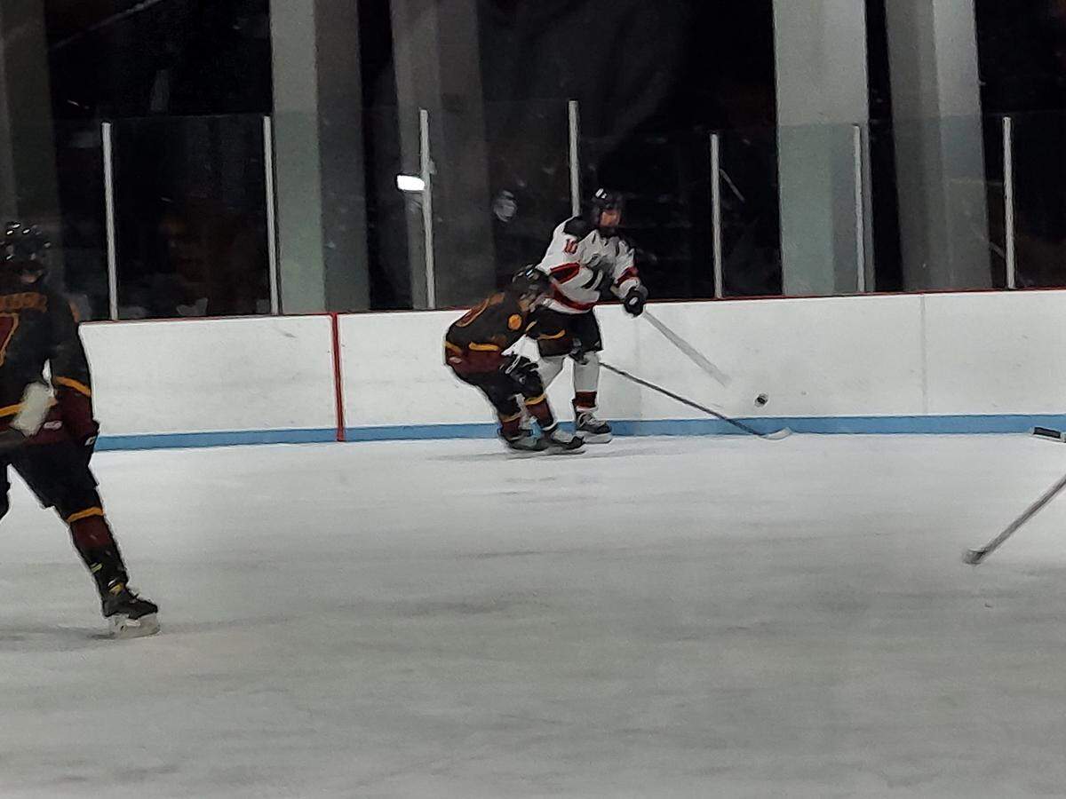 Highland senior Dylan Kreke fires the puck off the boards past an East Alton Wood River forward during an MVCHA game Thursday, Jan. 19, at Granite City Ice Rink. The Bulldogs ultimately prevailed 3-1.