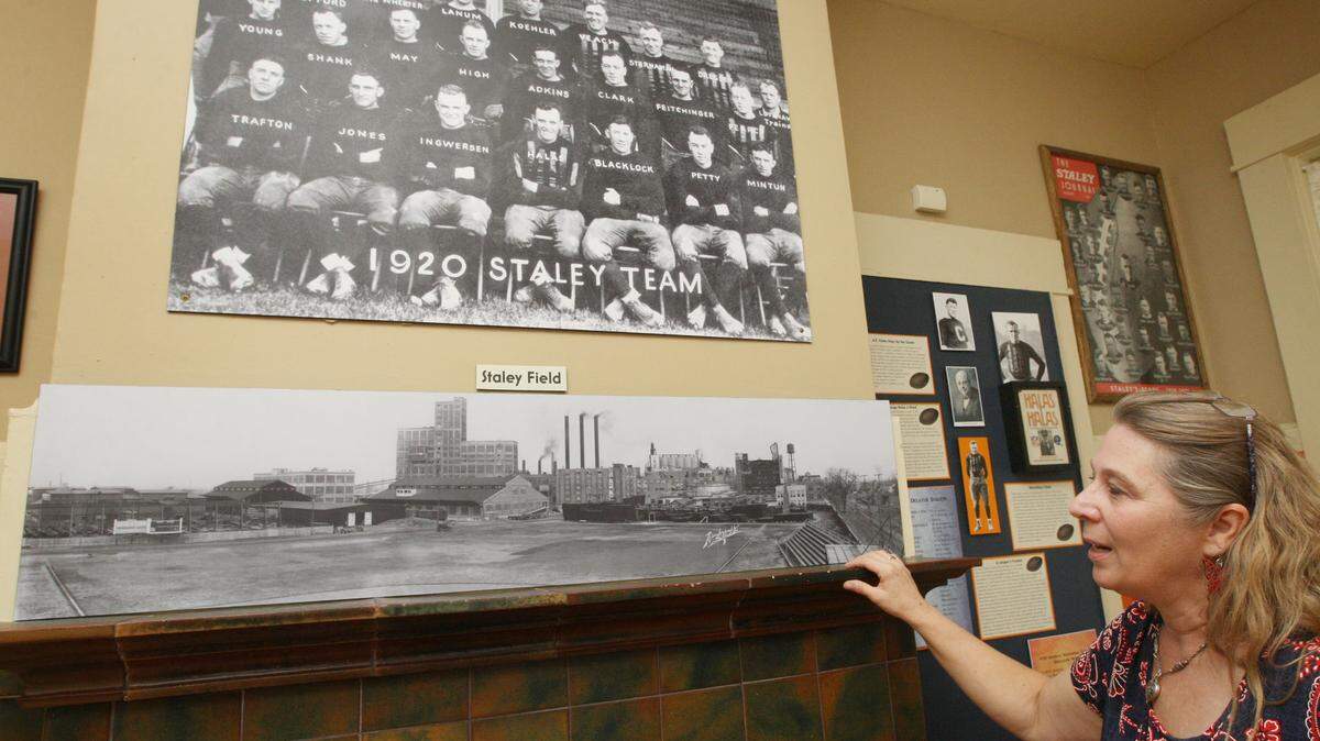 Staley Museum director Laura Jahr shows a vintage team photo of the Decatur Staleys and a photo of their stadium both taken in 1920 on display at the museum.