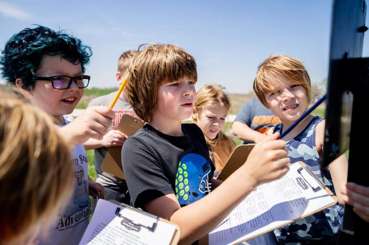 Wyatt Billings, a 4th grade teacher at the Barry, Ill.-based Western Elementary School, looks over an educational placard alongside Briggs Renecker, right, and other classmates on Wednesday, April 12, 2023, at the New Philadelphia National Historic Site in New Philadelphia, Ill.