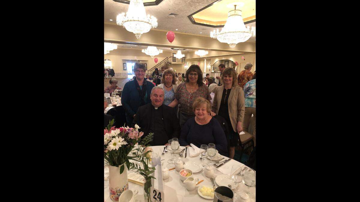 The Rev. Michael G. McGovern, seated on left, celebrates at a Woman of the Year function in 2019 with parishioners at St. Raphael the Archangel Parish in Old Mill Creek.
