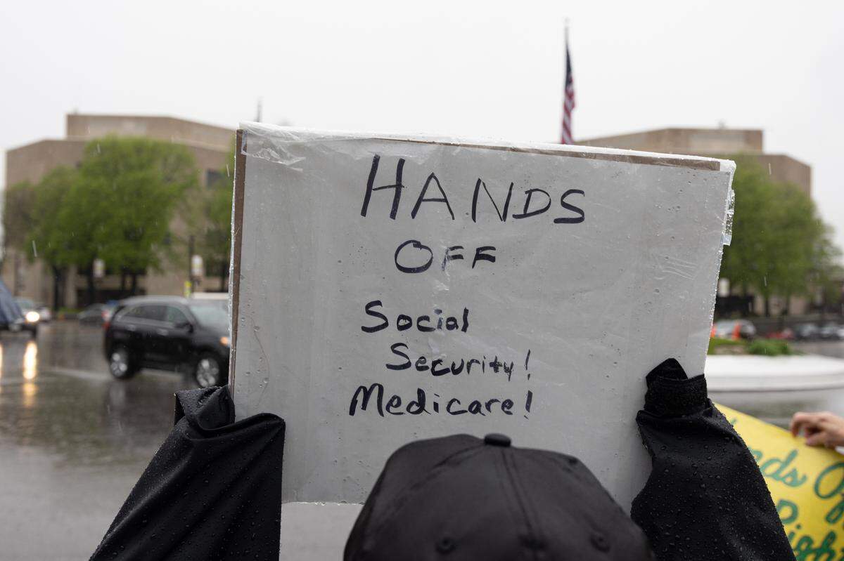 A protestor holds up a sign saying “Hands off Social Security! Medicare!” during a protest at Belleville’s Public Square.