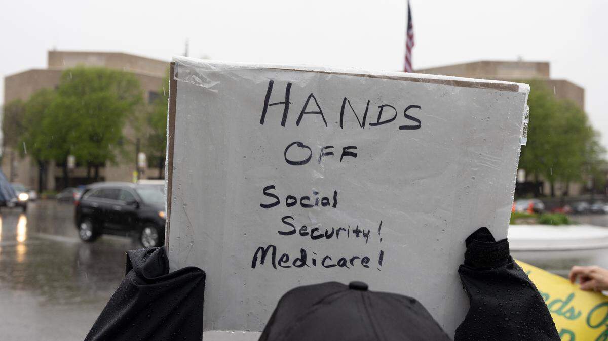 A protestor holds up a sign saying “Hands off Social Security! Medicare!” during a protest at Belleville’s Downtown Public Square in April.