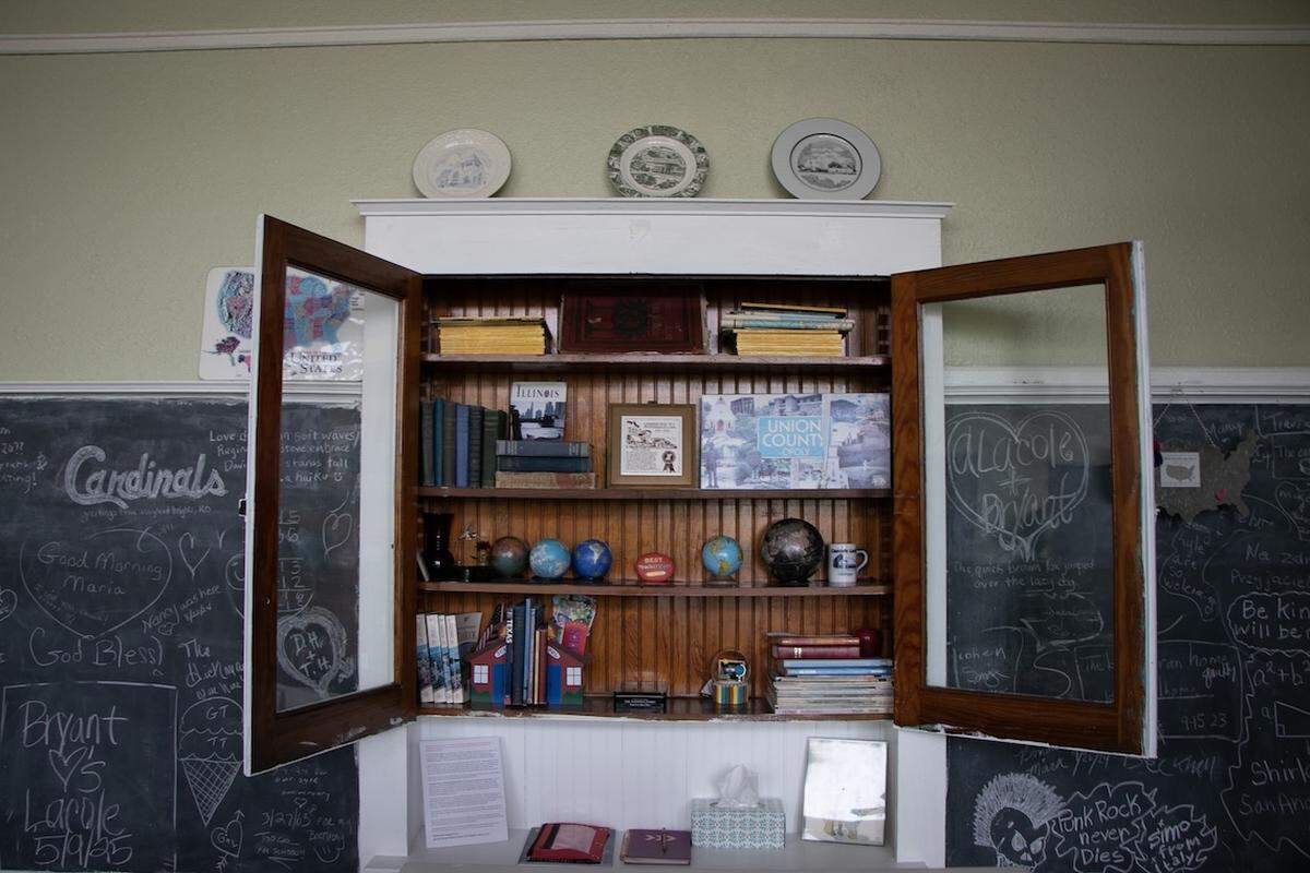 Open cabinet doors in a Davie School Inn guest room display globes and other teacher-themed decorations.