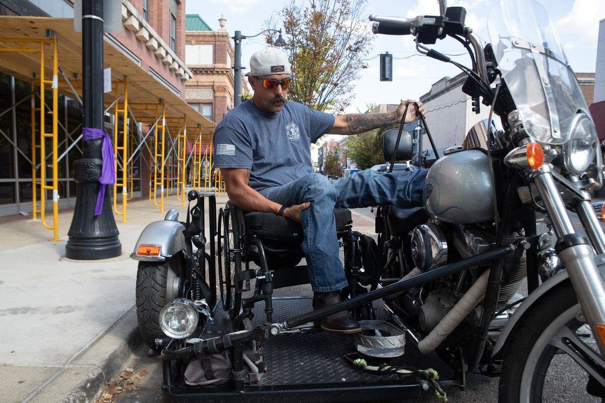 Brad Henke slides from his wheelchair into his motorcycle along Belleville’s Main St. “I built the piece so I can secure the wheelchair and transfer to it all from the driver’s seat,” Henke said. Henke has a TikTok account, where he uploaded a video of himself getting on and off the bike, citing a lack of demonstrative videos from other disabled riders as inspiration.