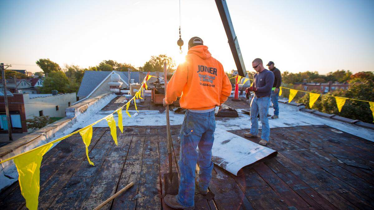 Workers of Joiner Sheet Metal & Roofing preforming a task on a roof. The company has operated in Greenville since 2005, but plans to move operations to Highland within the month.