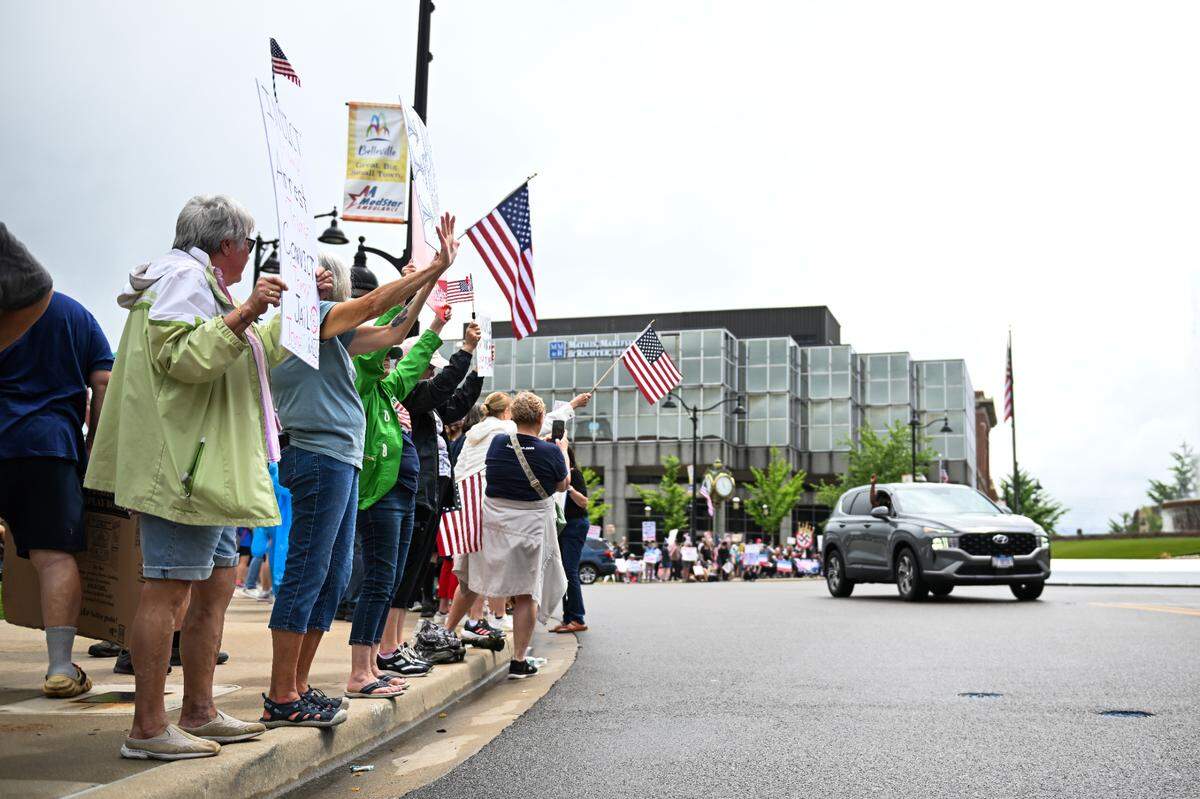 A passenger in a passing car waves to protesters at the “No Kings” demonstration in Belleville’s Public Square Saturday, June 14, 2025.