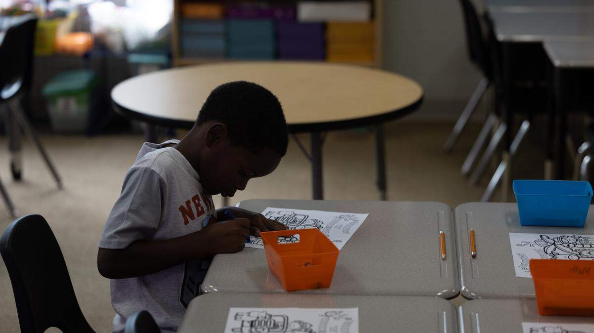 A first grader sits down to color on the first day of the 2025 school year at Dunbar Elementary in East St. Louis.