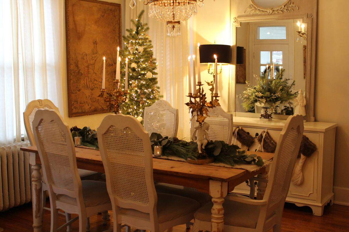 A farmhouse table in the dining room of the Hettenhausen home in Belleville is decorated with a canvas-like runner, gold and cherub candelabras and garland with pine cones and eucalyptus.