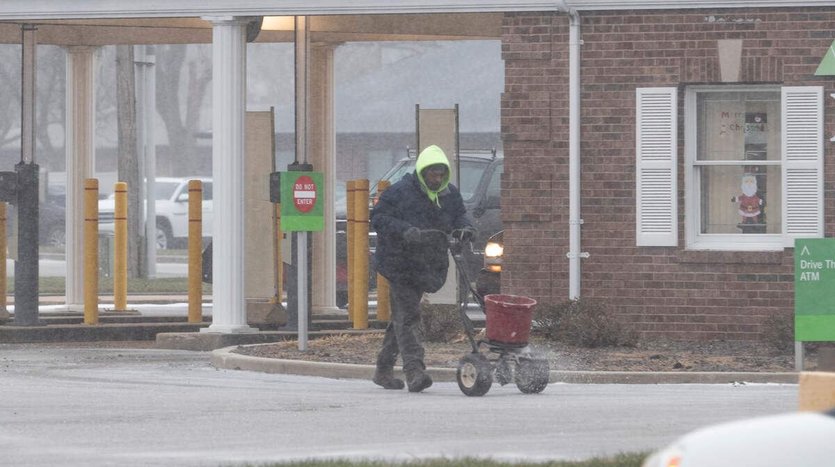 A worker spreads ice melt on the Region’s Bank parking lot just before noon on Thursday as temperatures started to drop with gusty winds, snow and sleetThe metro-east will be under a wind chill warning starting at 6 p.m. Thursday, Dec. 22, through noon Friday, Dec. 23, according to the National Weather Service of St. Louis.