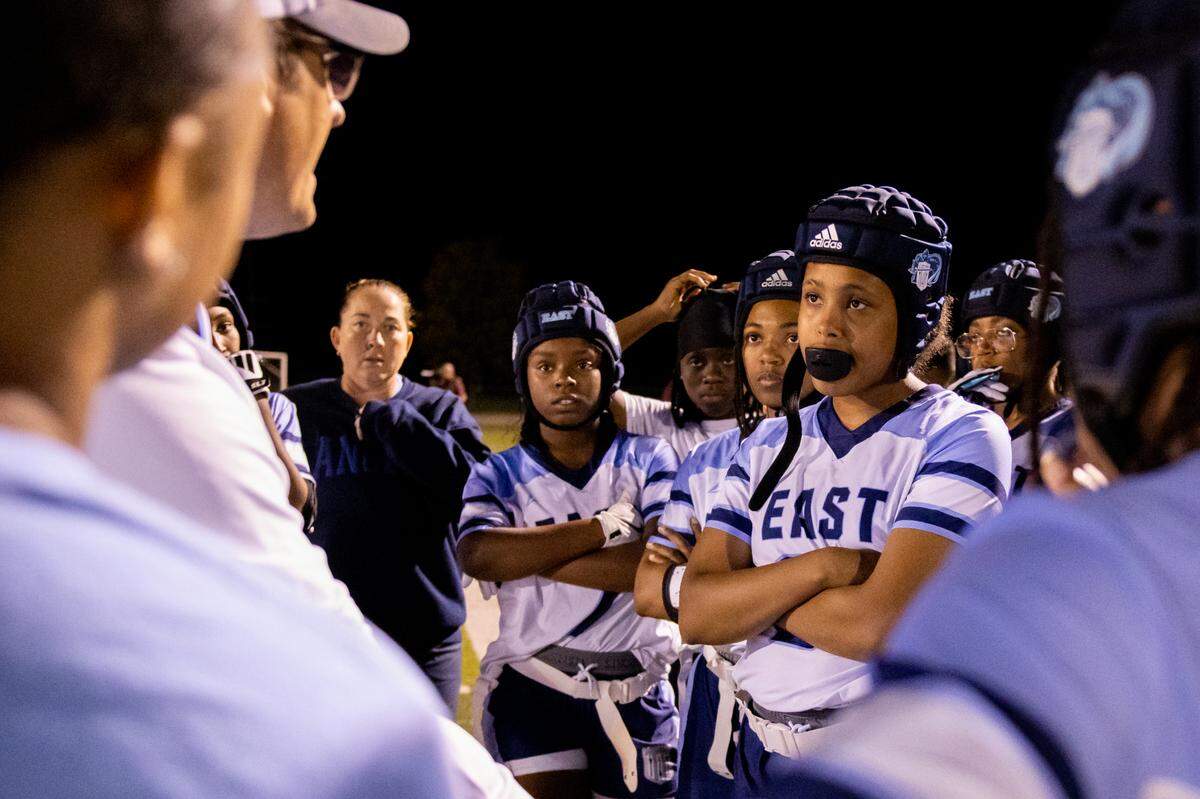 Belleville East’s Aliyah Anderson, right, and her teammates listen to head coach Doug Zerjal for feedback during a girls flag football game on Wednesday.