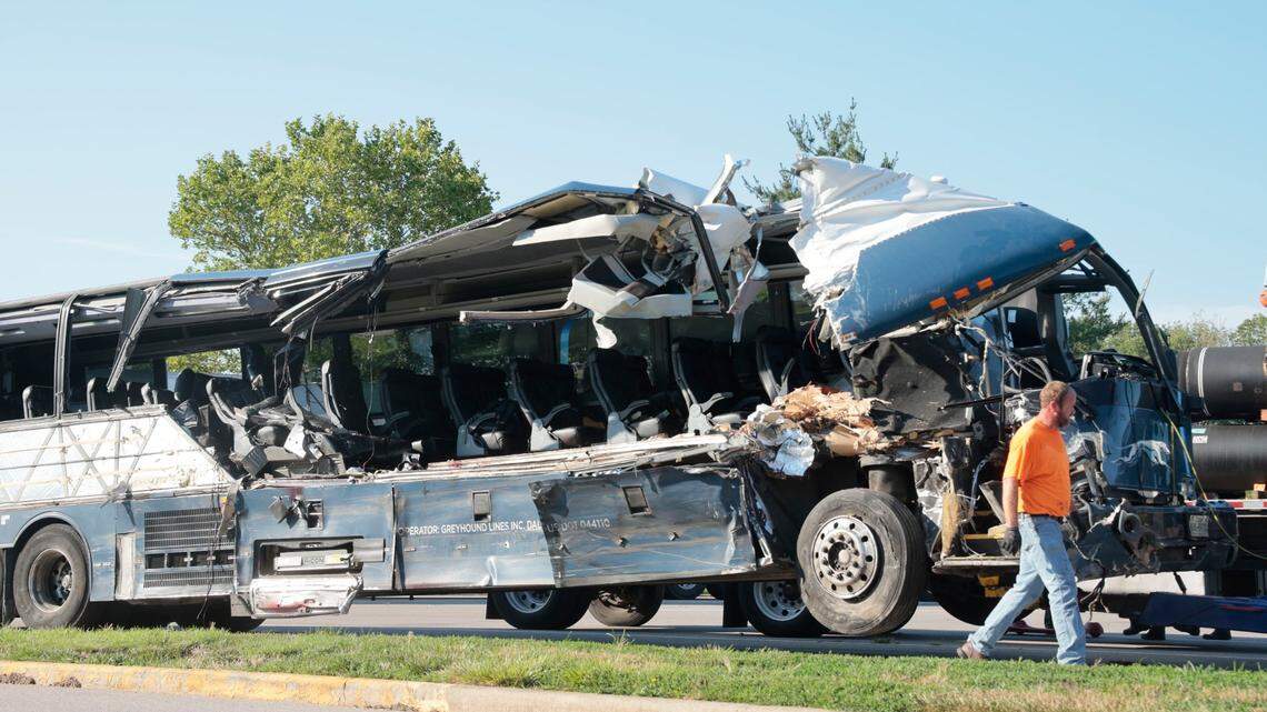 A worker helps clear the wreckage of a Greyhound bus that collided with tractor-trailers on the exit ramp to a rest area on westbound Interstate 70 in Highland, Ill., on Wednesday, July 12, 2023. (Christian Gooden/St. Louis Post-Dispatch via AP)