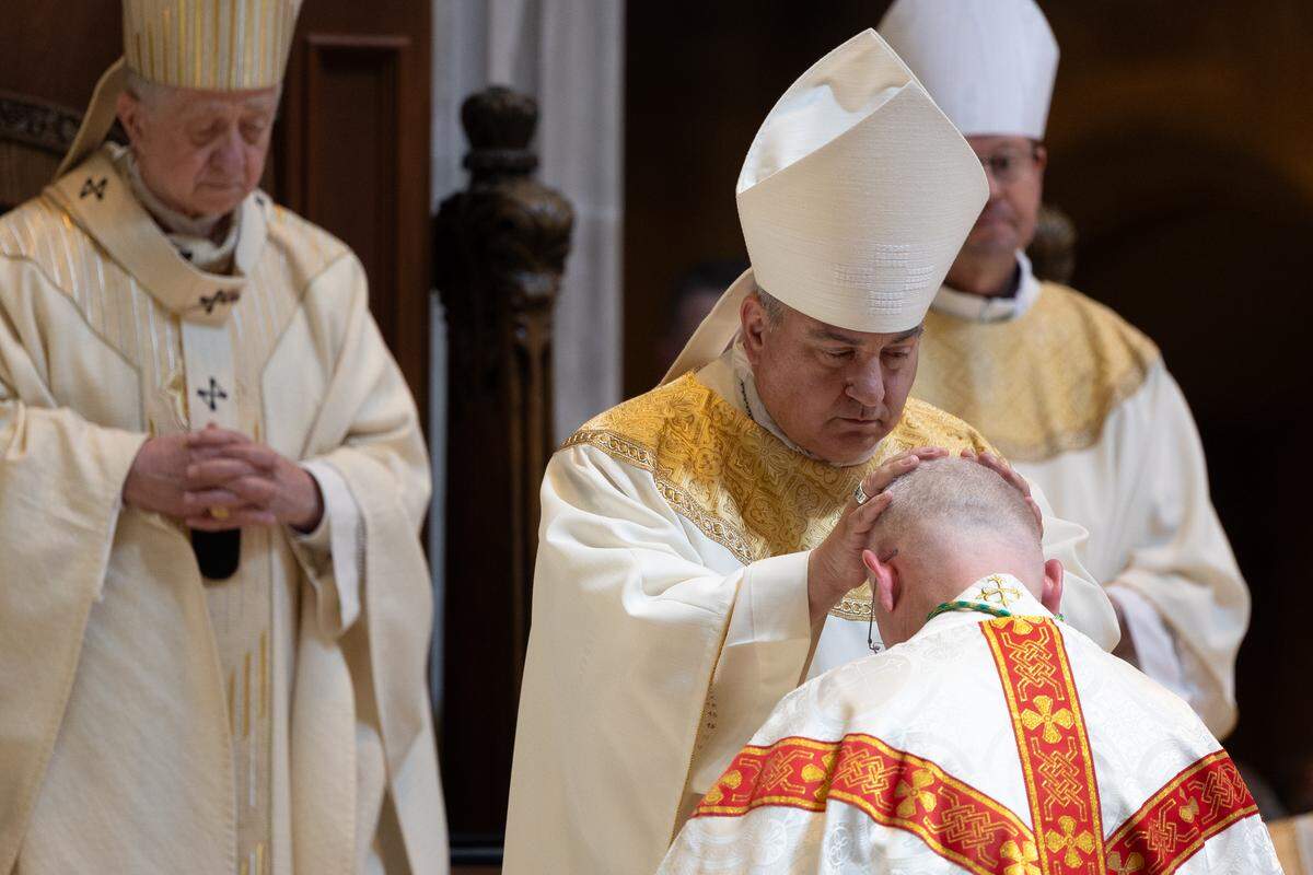 Archbishop Michael McGovern, former bishop of Belleville who now leads the Omaha archdiocese, lays his hands on Bishop-Elect Godfrey Mullen during Mullen’s installation at the Cathedral of St. Peter on Friday. At left is Cardinal Blase Cupich, archbishop of Chicago.