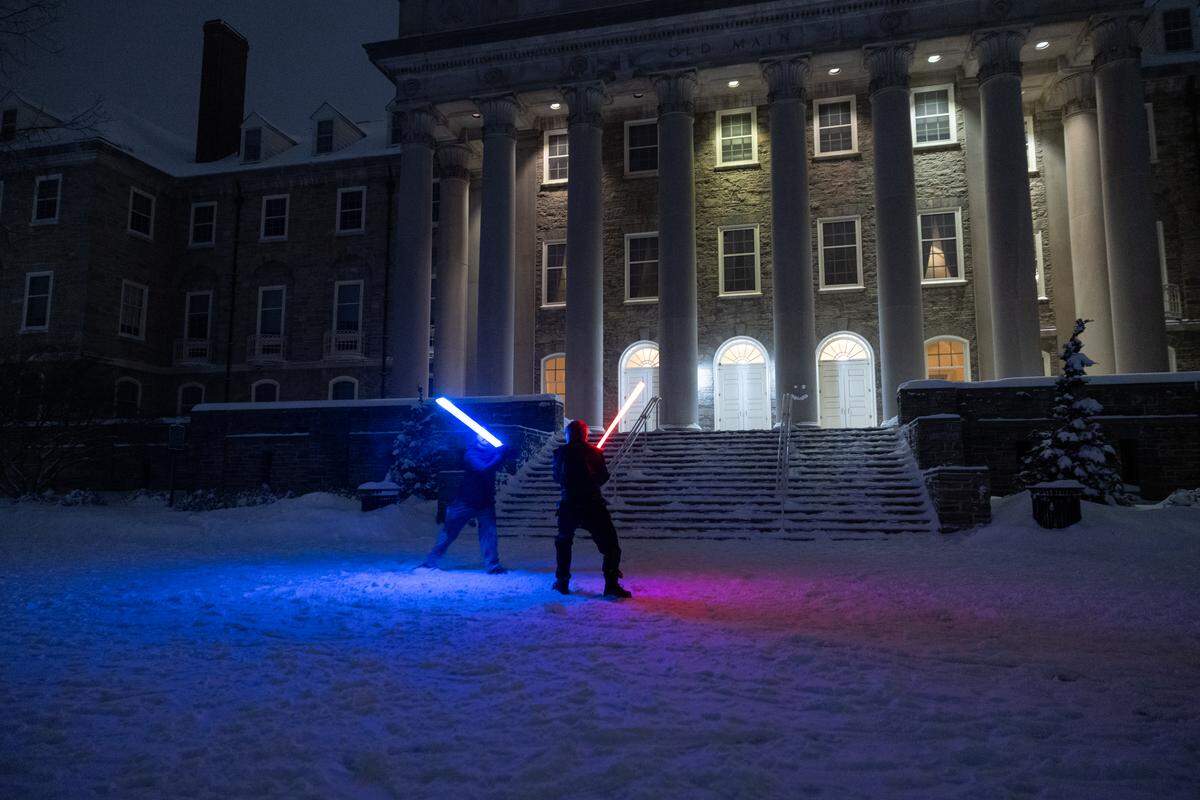 Penn State students Sean Lydon, left, and Kyle Siler, right, participate in a lightsaber duel in from of Old Main on Sunday.