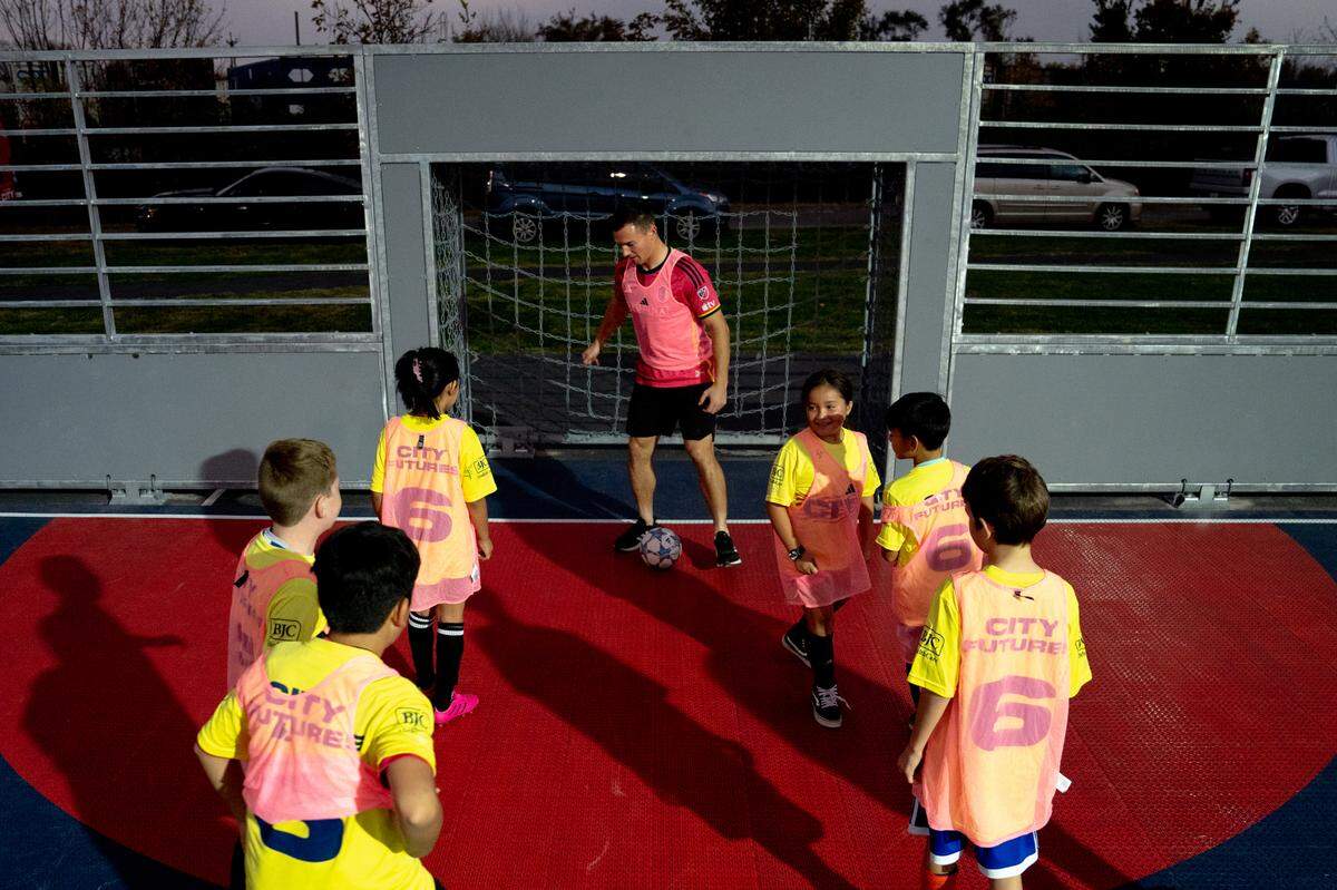 St. Louis City SC defender Kyle Hiebert (22) plays soccer with half a dozen children on Thursday, Oct. 26, 2023, during the dedication of a community mini pitch at Granby Park in Fairmont City.