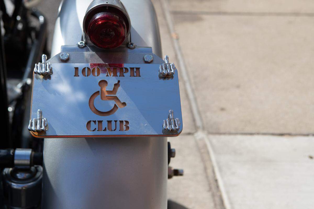 A sign saying “100 MPH CLUB” sits on the side of Henke’s motorcycle to add a bit of personal ironic humor to his situation.