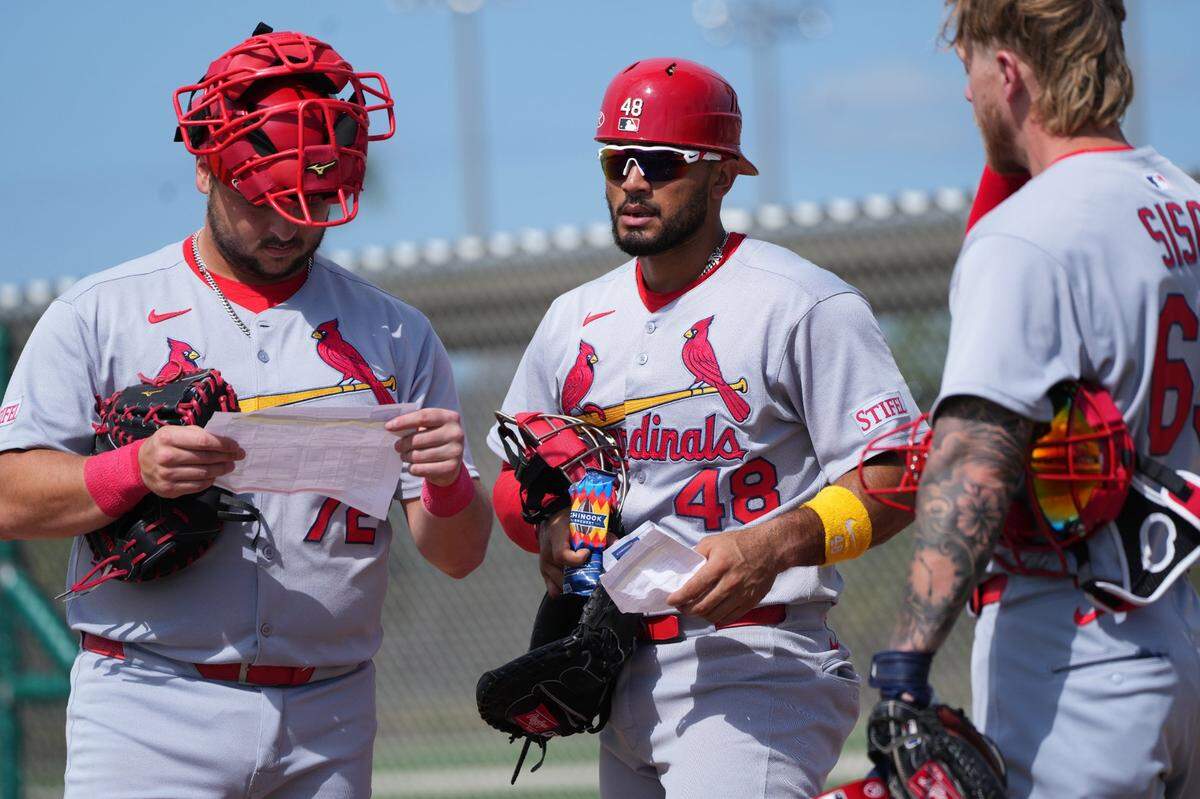 Feb 17, 2025; Jupiter, FL, USA;  St. Louis Cardinals catcher Jimmy Crooks (72), catcher Ivan Herrera (48) and catcher Chance Sisco (65) look over the schedule at spring training. Mandatory Credit: Jim Rassol-Imagn Images