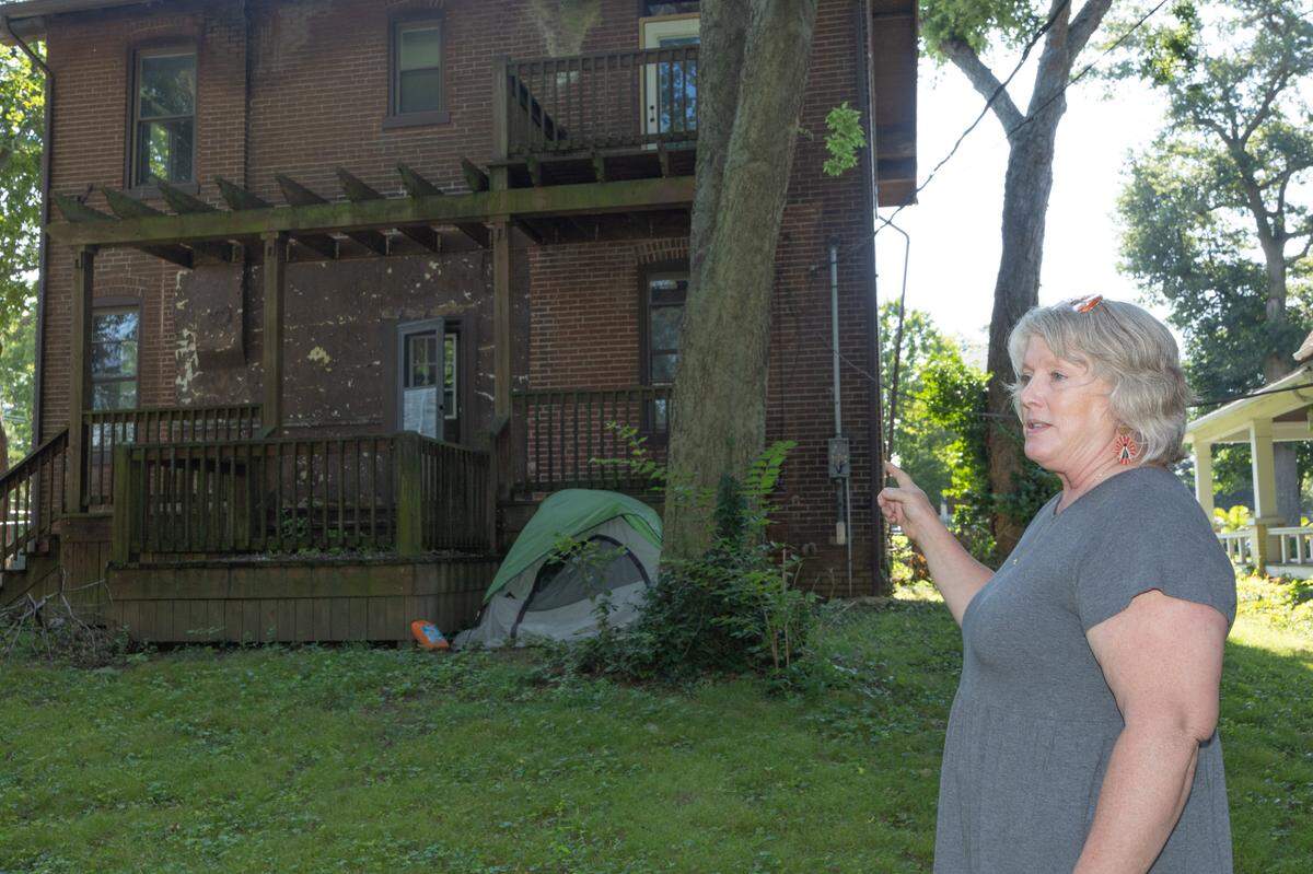 Lori Creason Powell points to a squatter’s tent behind a derelict home at 609 S. Jackson St. in Belleville. Powell, who lives around the corner, wants the owner, Main Street Redevelopers, to either fix it or sell it.