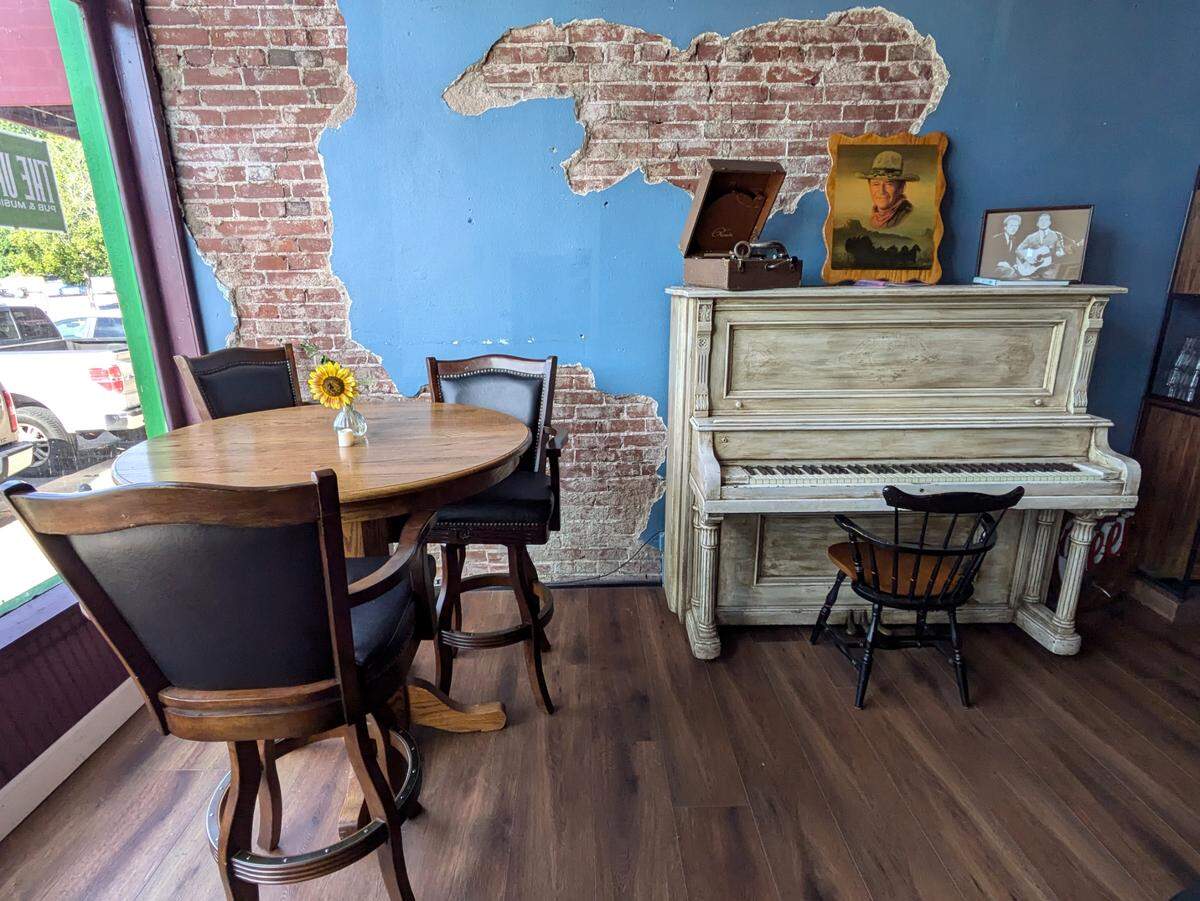 One front corner of The Upright offers pub-height table seating and features an upright piano. Note the exposed brick sections of wall.