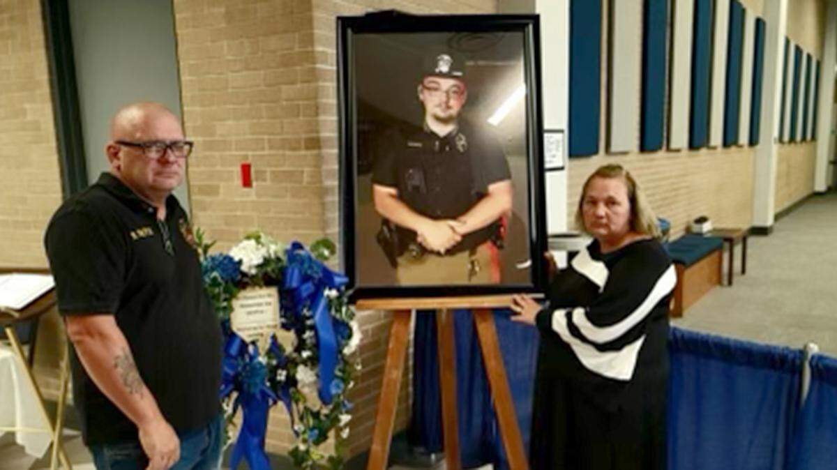 Brian Pierce Sr. and Tammy Pierce show a photo of their son, Brooklyn police officer Brian Pierce Jr., at John A. Logan College in Carterville, where his funeral service was held on Oct. 6, 2021. He lived in Carbondale.